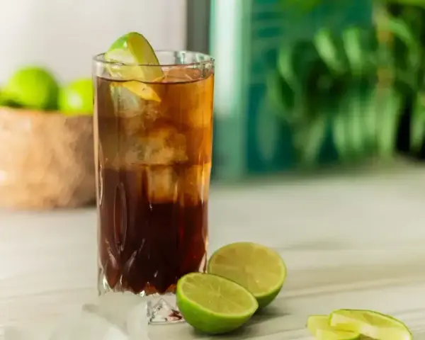 Orzeźwiający Cuba Libre z lodem i limonką, gotowy do świętowania.
