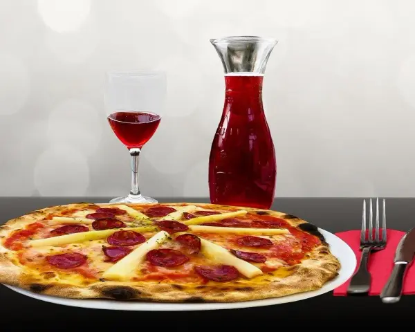 Pizza z kiełbasą i szparagami, kieliszek czerwonego wina i karafka. Idealne połączenie, zastanawiasz się, jakie wino do pizzy?