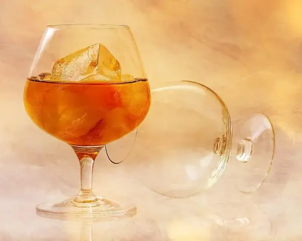 Kieliszek brandy z lodem, obok pusty, zapraszają do degustacji. Oto jak pić brandy, by docenić jej smak.