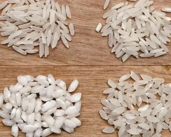 Cztery rodzaje ryżu, w tym ryż do risotto, ułożone na drewnianym tle.