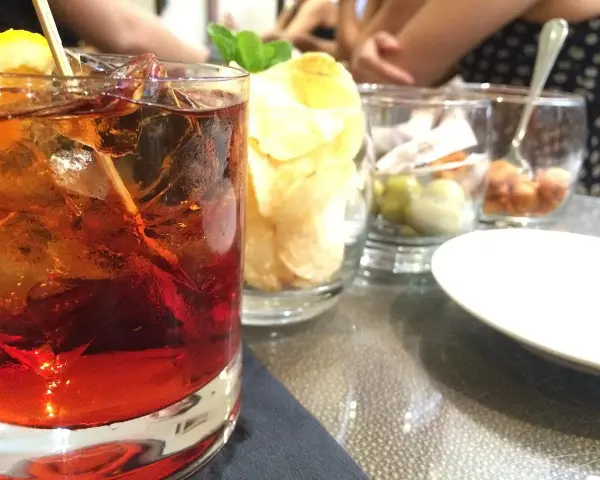 Orzeźwiający drink z rumem, lodem i cytryną, idealny do delektowania się w letni wieczór. Obok przekąski i chipsy.