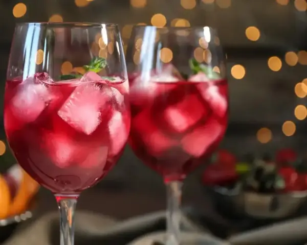 Dwa orzeźwiające drinki z prosecco i sprite, pełne lodu i listków mięty, na tle migoczących światełek.
