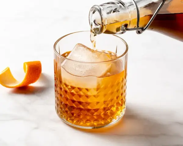Amaretto co to? Bursztynowy likier migdałowy nalewany do szklanki z lodem, ozdobionej skórką pomarańczy.