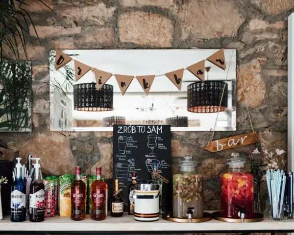 Stół z butelkami alkoholu, sokami i dzbankami z owocami, gotowy na drinki na wesele.