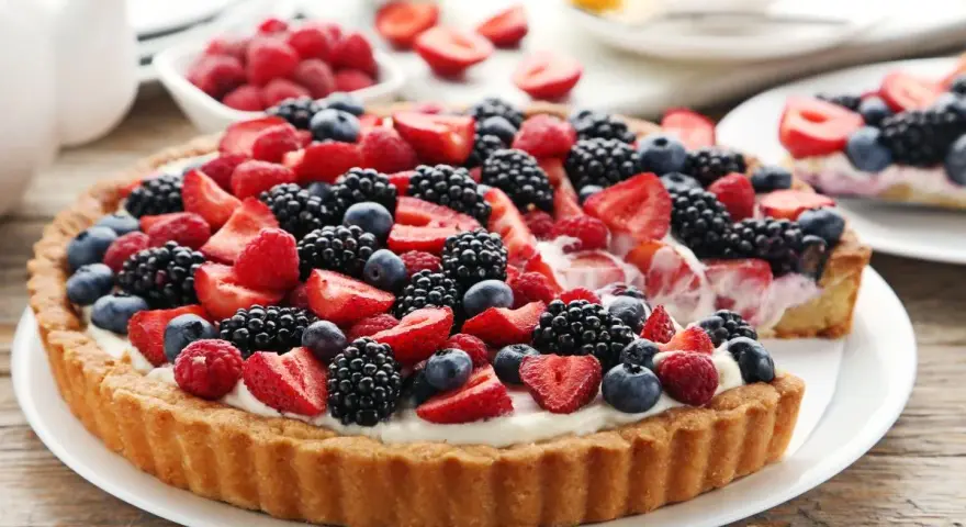 Pyszna tarta z mascarpone, udekorowana świeżymi malinami, borówkami i jeżynami. Idealna na letnie popołudnie.