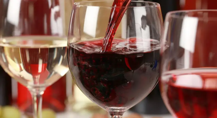 Czerwone wino leje się do kieliszka, obok stoi kieliszek białego wina. To może być najdroższe wino na świecie.