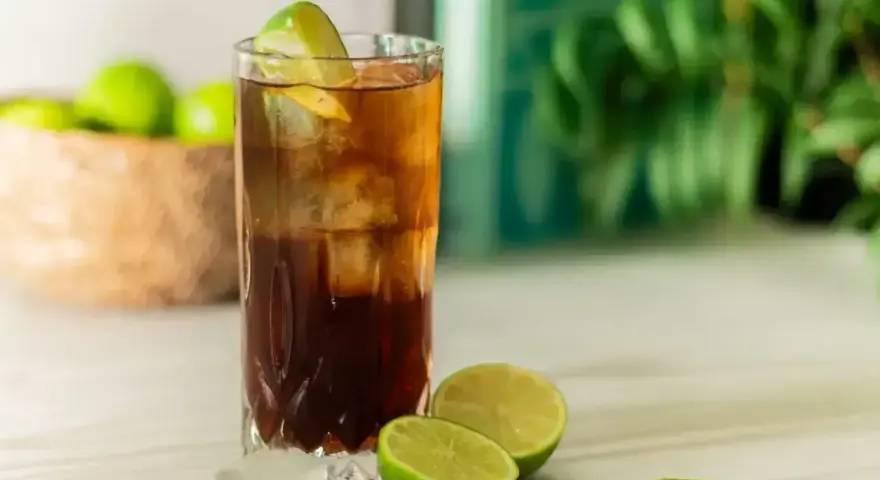 Orzeźwiający Cuba Libre z lodem i limonką, gotowy do świętowania.