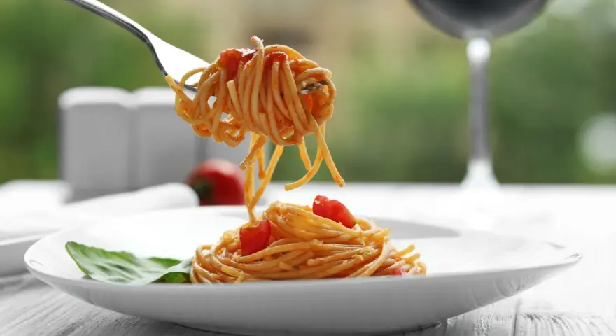 Widok na talerz z makaronem spaghetti i pomidorkami, idealny do rozważań, jakie wino do carbonary.