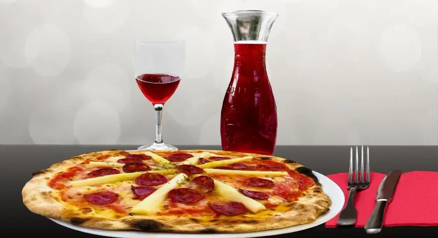 Pizza z kiełbasą i szparagami, kieliszek czerwonego wina i karafka. Idealne połączenie, zastanawiasz się, jakie wino do pizzy?