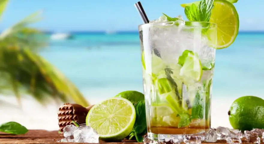 Orzeźwiające drinki z miętą i limonką na tle plaży. Idealne na upalne dni.