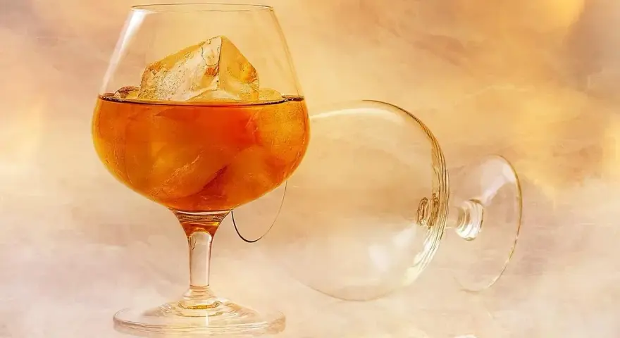 Kieliszek brandy z lodem, obok pusty, zapraszają do degustacji. Oto jak pić brandy, by docenić jej smak.
