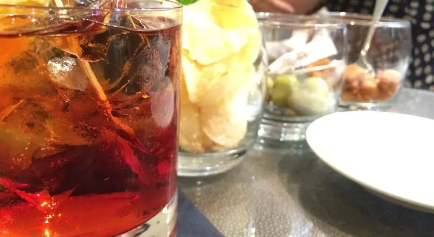 Orzeźwiający drink z rumem, lodem i cytryną, idealny do delektowania się w letni wieczór. Obok przekąski i chipsy.