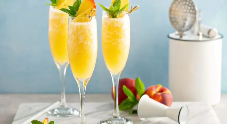 Orzeźwiający drink z prosecco i sokiem pomarańczowym, udekorowany brzoskwinią i miętą. Idealny na letnie popołudnie.