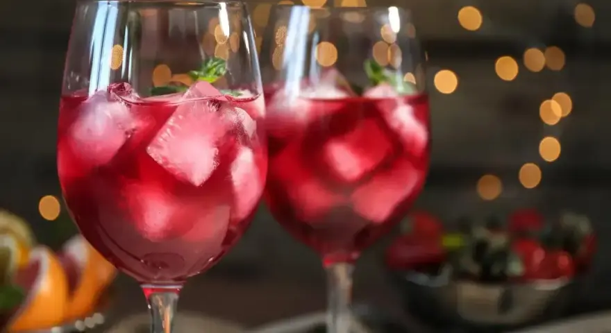 Dwa orzeźwiające drinki z prosecco i sprite, pełne lodu i listków mięty, na tle migoczących światełek.