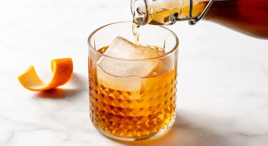 Amaretto co to? Bursztynowy likier migdałowy nalewany do szklanki z lodem, ozdobionej skórką pomarańczy.