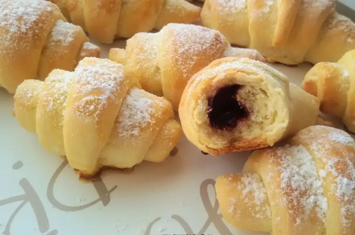 Pyszne rogaliki krucho drożdżowe, posypane cukrem pudrem, z nadzieniem z dżemu. Idealne na śniadanie.