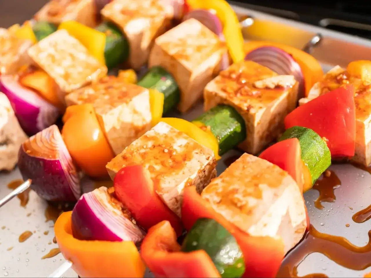 Kolorowe szaszłyki z tofu, papryką, cukinią i czerwoną cebulą, polane sosem. Idealne na grilla!