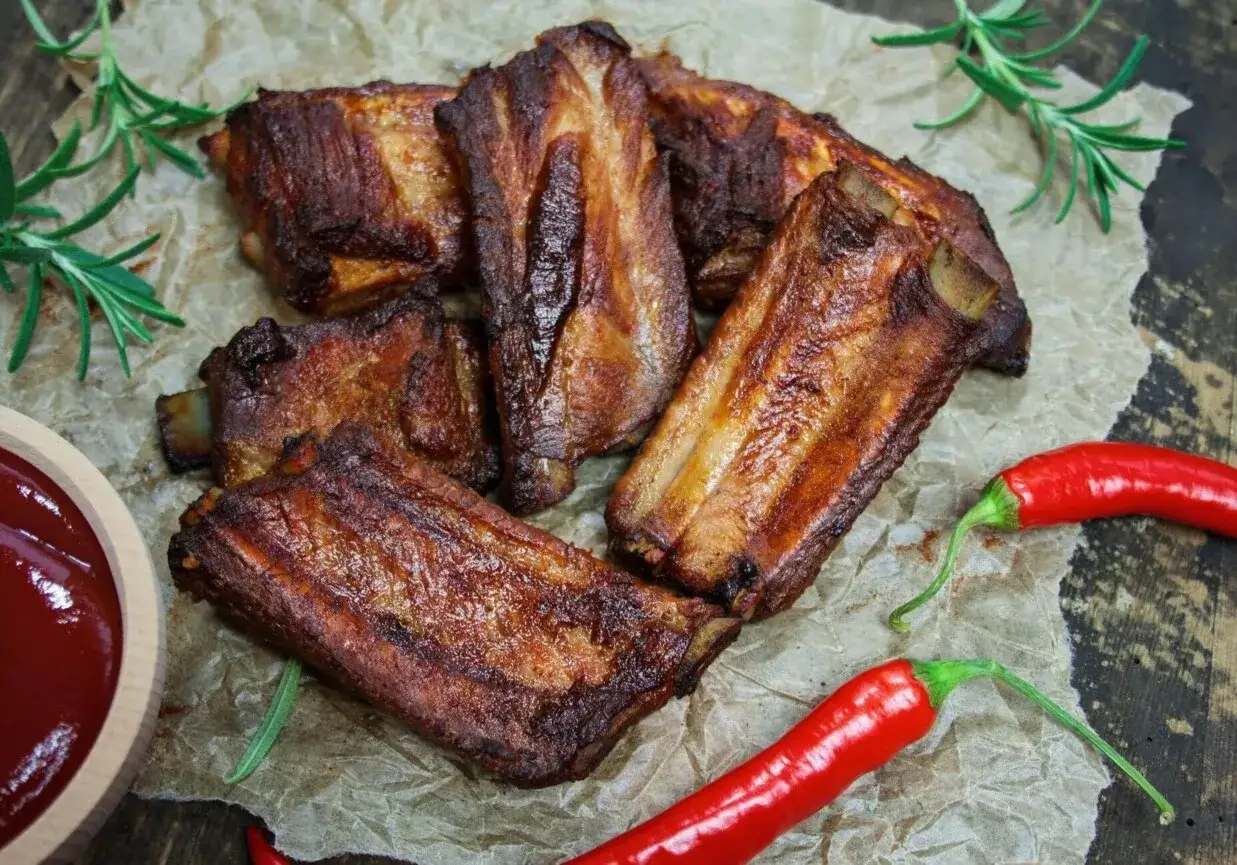 Soczyste żeberka w coli, pieczone do perfekcji, podane z ostrymi papryczkami chili i gałązkami rozmarynu.