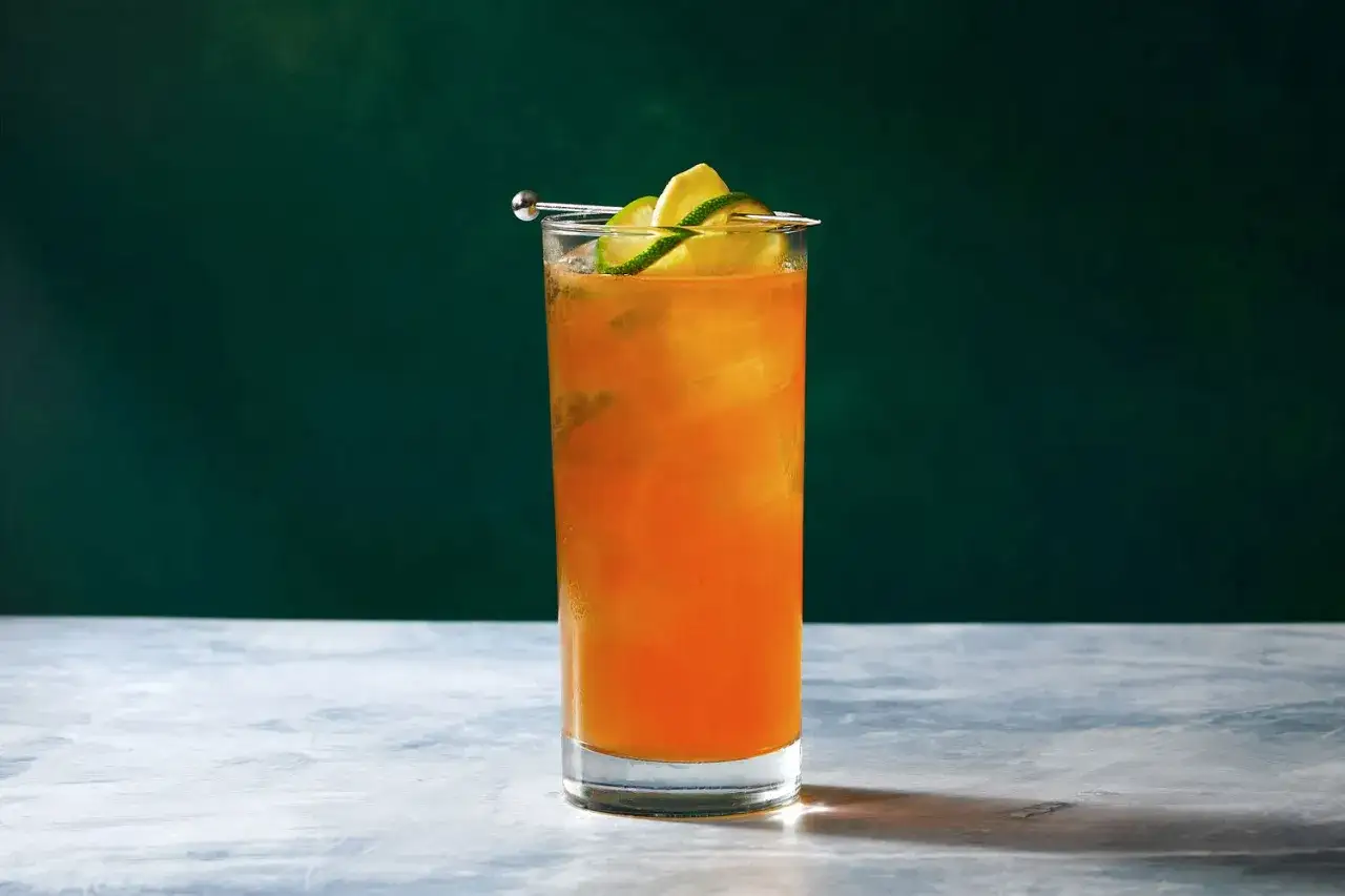 Pomarańczowy drink z lodem i plasterkami limonki, idealny na dark and stormy wieczór.