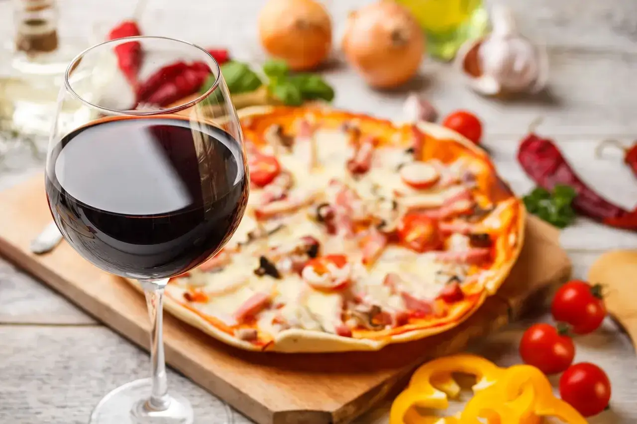 Idealne połączenie: kieliszek czerwonego wina i pizza. Zastanawiasz się, jakie wino do pizzy wybrać? Ten obrazek podpowiada!