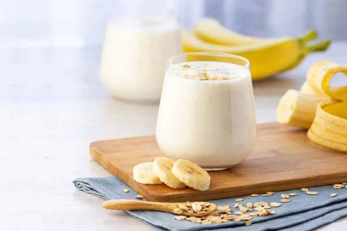 Pyszny drink z sokiem bananowym, płatkami owsianymi i świeżymi bananami na drewnianej desce.