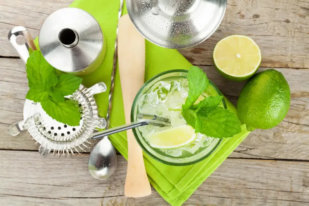 Orzeźwiający mohito drink z miętą i limonką, przygotowany z akcesoriami barmańskimi.