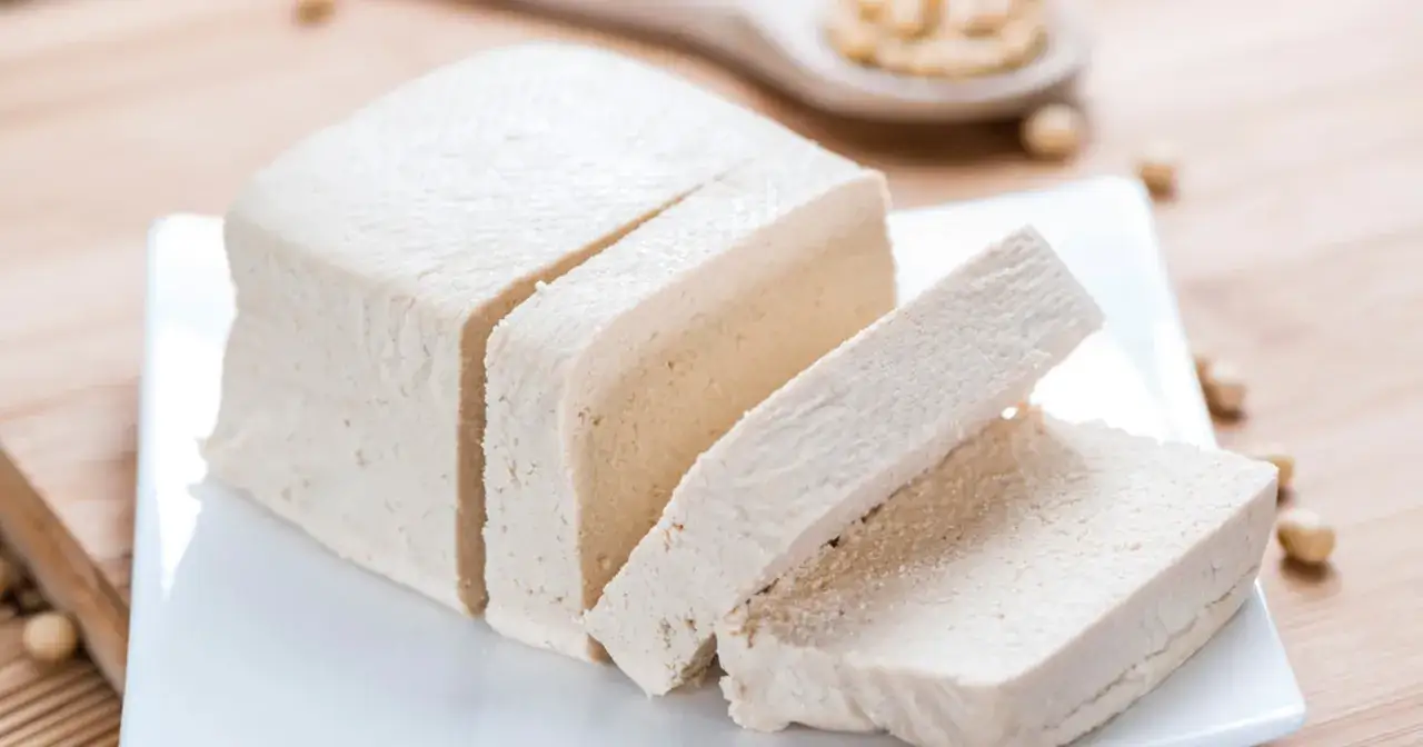 Kostka tofu, z czego jest zrobione? Z ziaren soi. Pokrojone na plastry, prezentuje swoją delikatną strukturę.