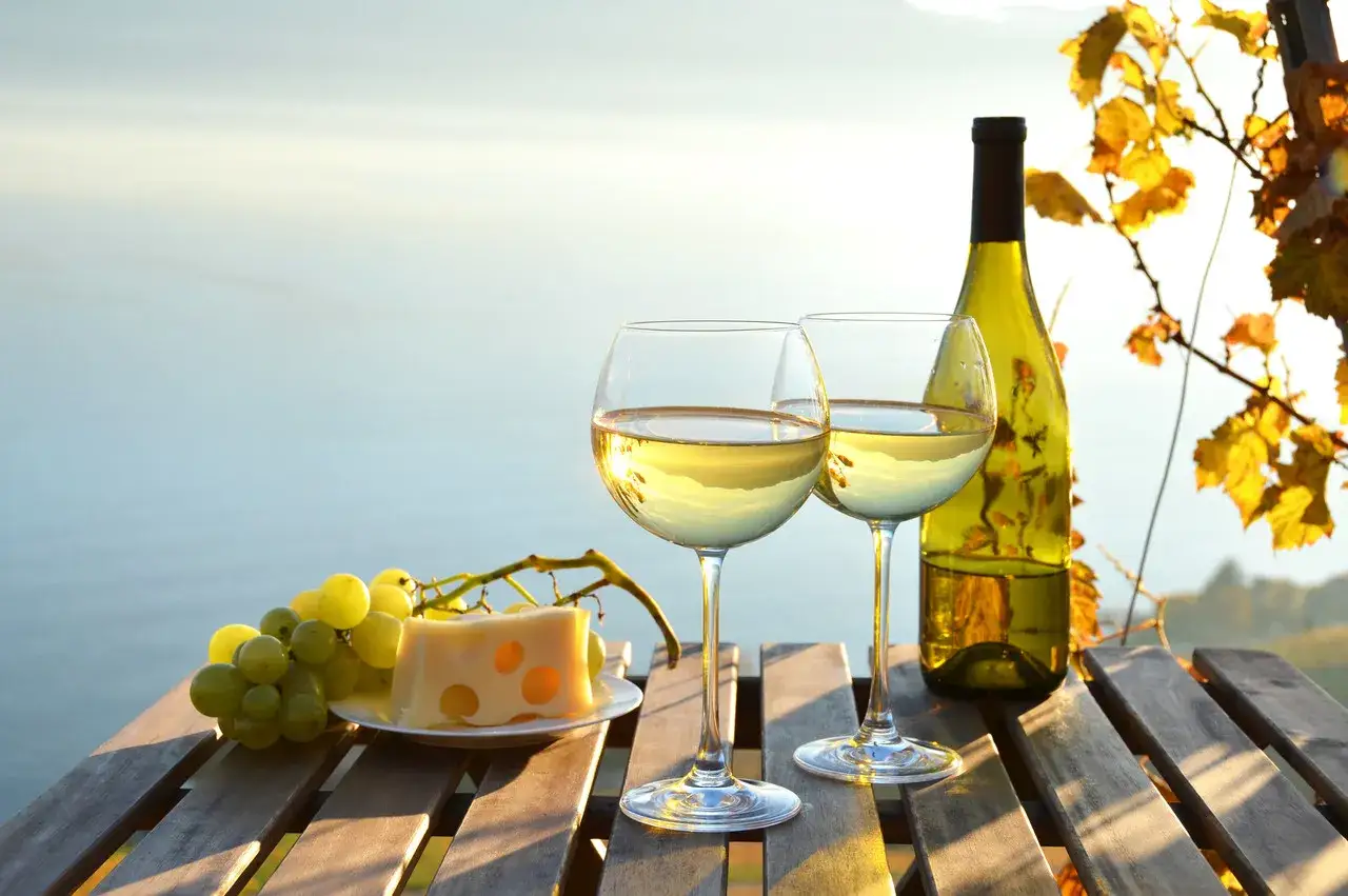 Dwa kieliszki orzeźwiającego drinka z białym winem, ser z winogronami na drewnianym stole.
