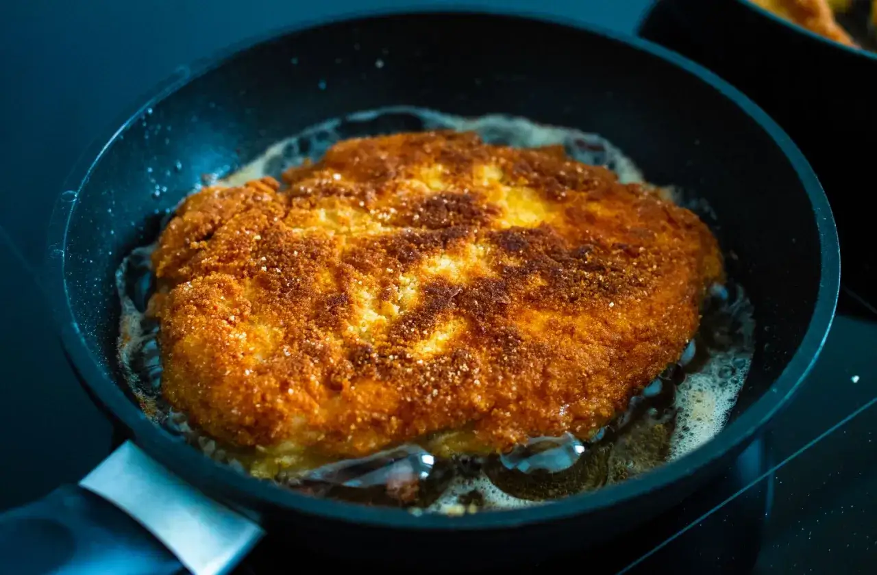 Złocisty kotlet schabowy smaży się na patelni. Sekret jak zrobić kotlety schabowe żeby były miękkie tkwi w odpowiednim smażeniu.