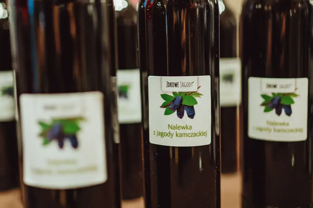 Butelki z nalewką z jagody kamczackiej. Etykieta z rysunkiem owoców i napisem 