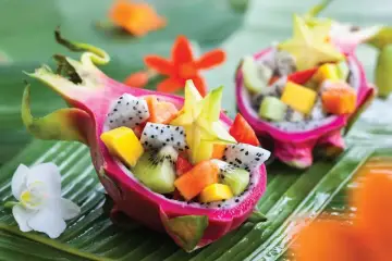 Smoczy owoc w formie miseczki wypełnionej egzotycznymi owocami: kiwi, mango, papają i karambolą.